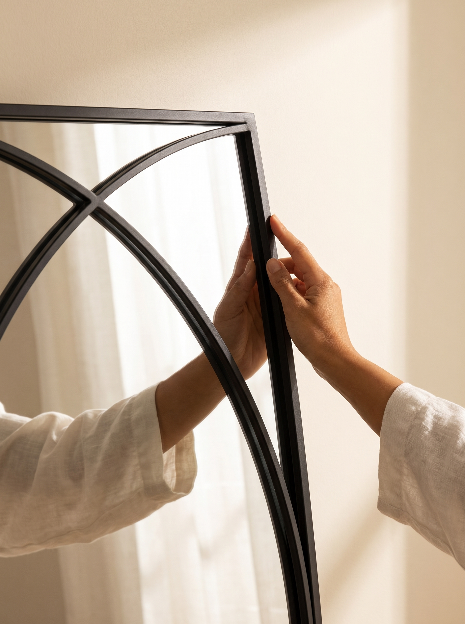 Close detail of the matte black iron frame on a LuxAura Arc Trio mirror panel