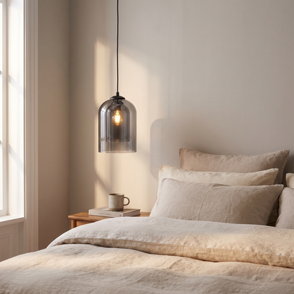 Smoky grey glass pendant light beside a bed