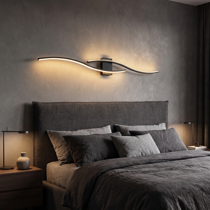 Black LED wave wall sconce with warm light above a bed