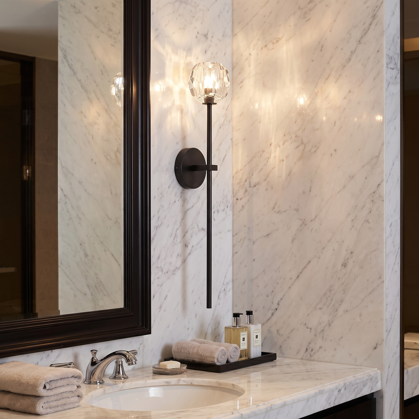 Balle crystal wall sconce beside a marble bathroom mirror