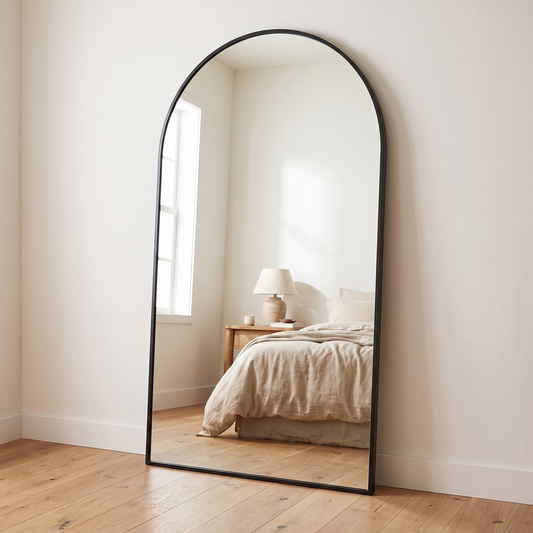 Oversized black arched full length mirror in a warm white bedroom