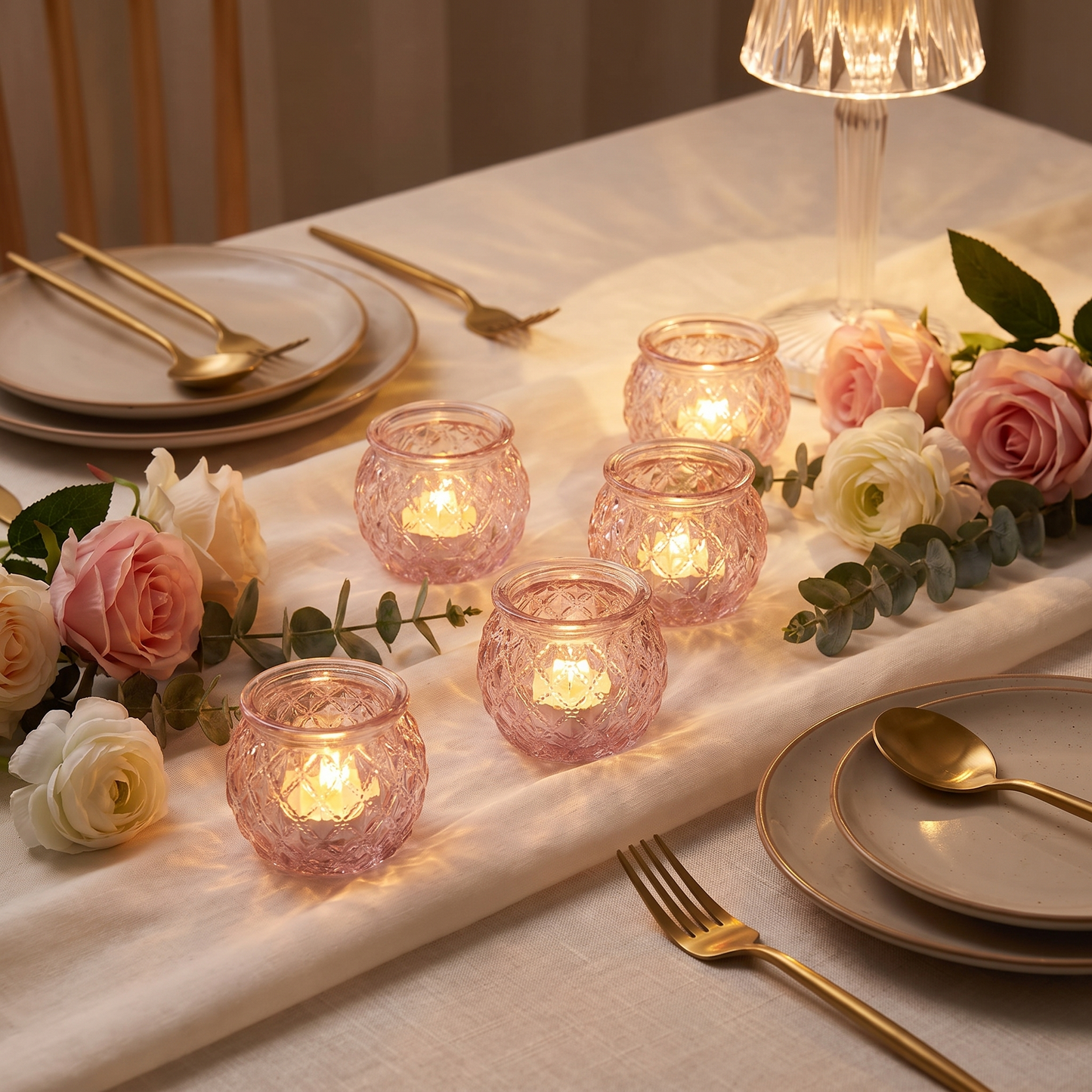Pink glass votive candle holders on a romantic dinner table