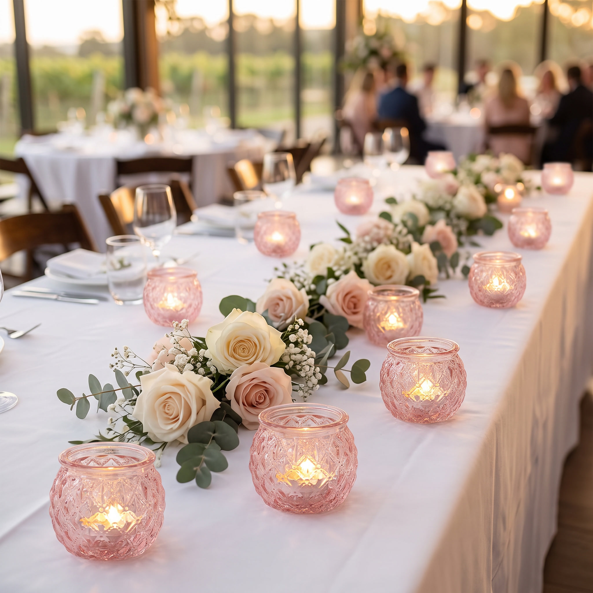 Pink votive candle holders along a wedding reception table