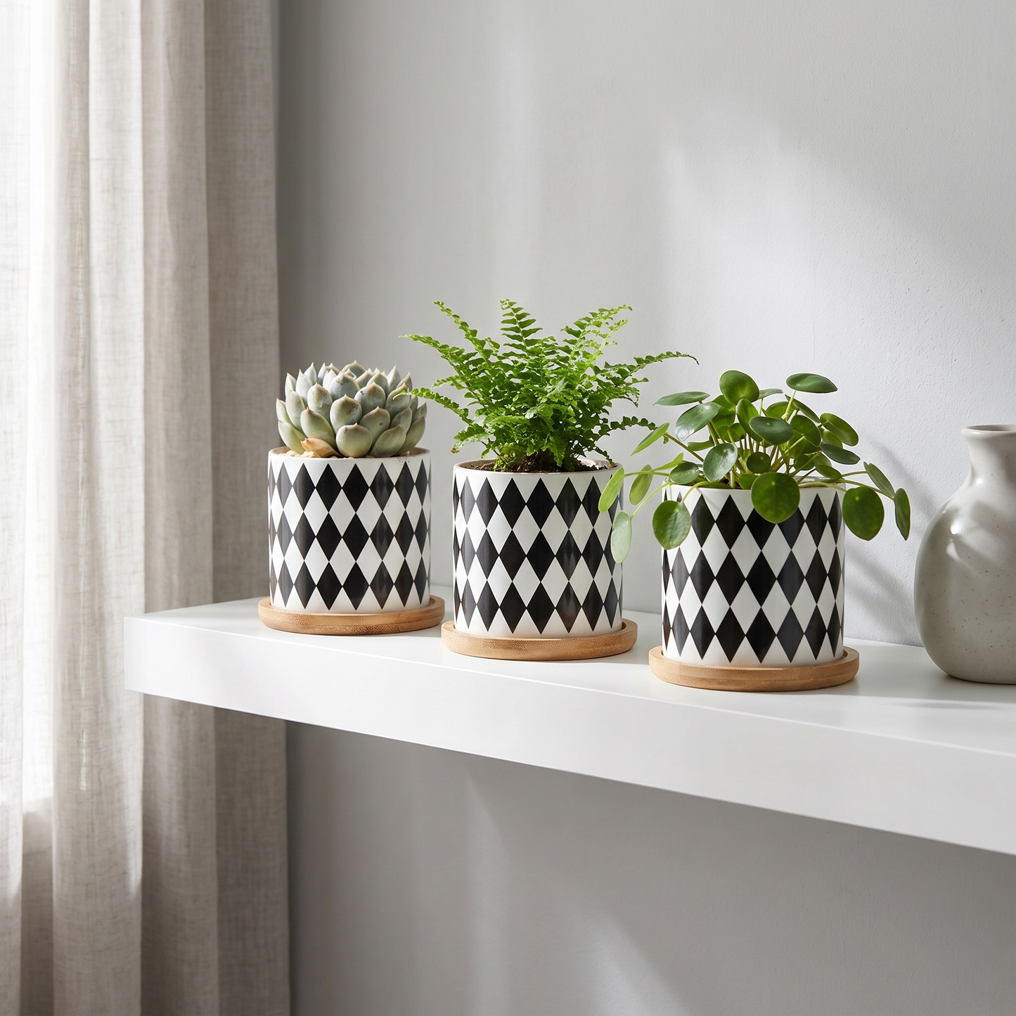 Set of three black and white planters on a floating shelf