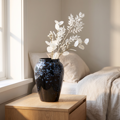 Handmade glazed ceramic vase on a bedside table