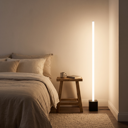 Slim LED floor lamp beside a bed