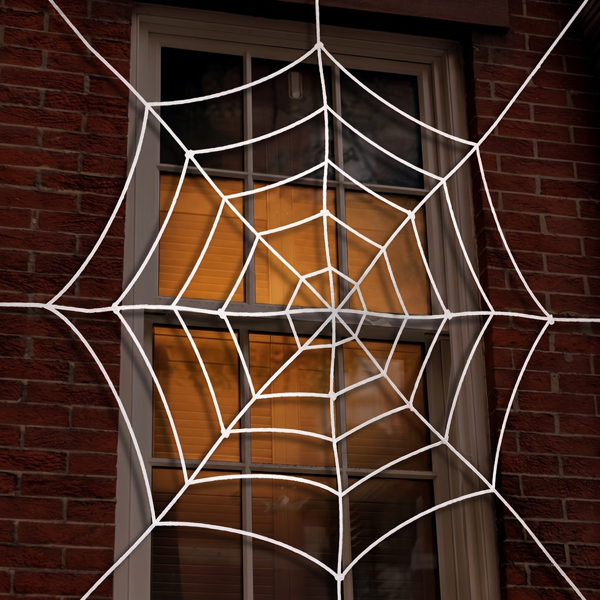 White spider web over a window at night