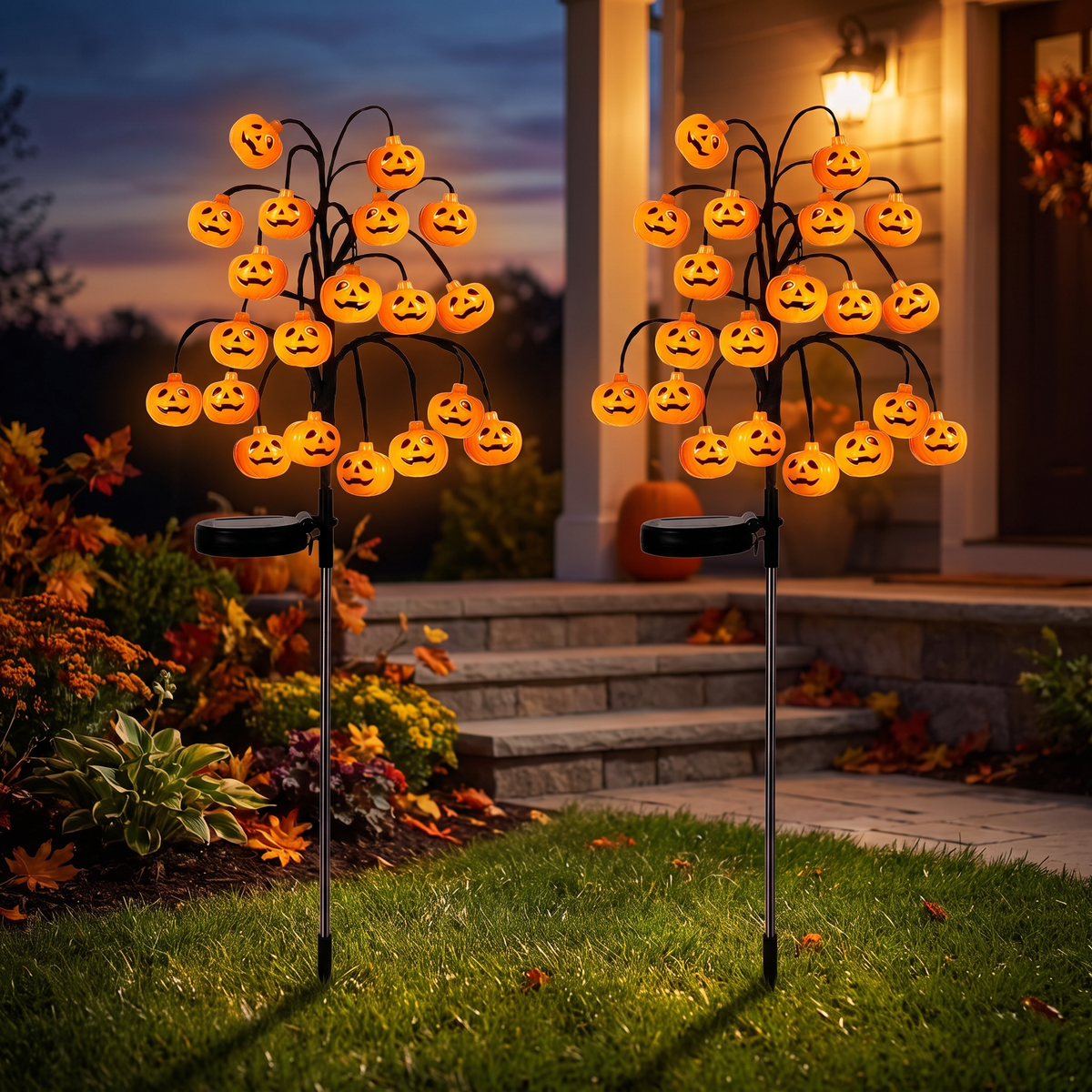 Solar pumpkin branch lights glowing either side of porch steps at dusk