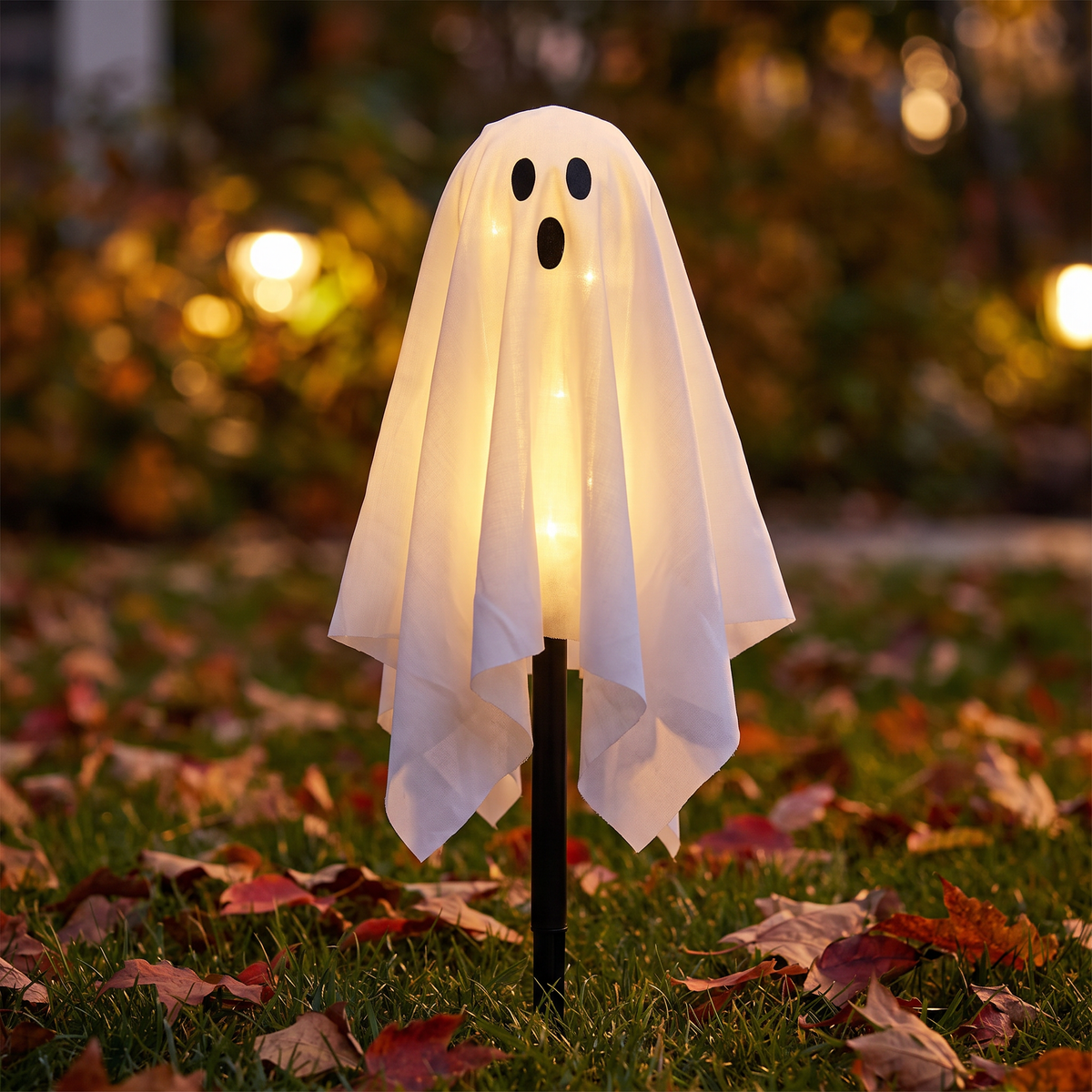Close-up of a glowing fabric solar ghost light on the lawn